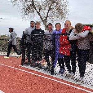 Athletes standing by fence with blankets, trying to keep warm between races